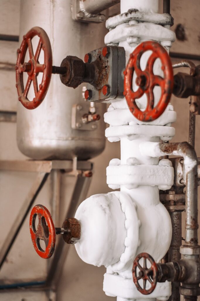 Industrial pipes and red valves in a factory setting